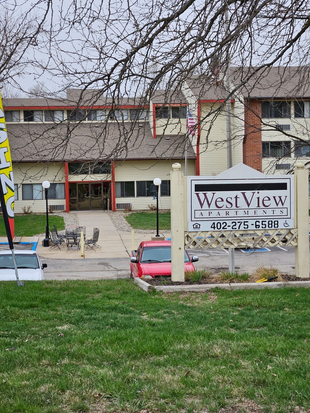 A sign for West View Apartments stands in front of a building.