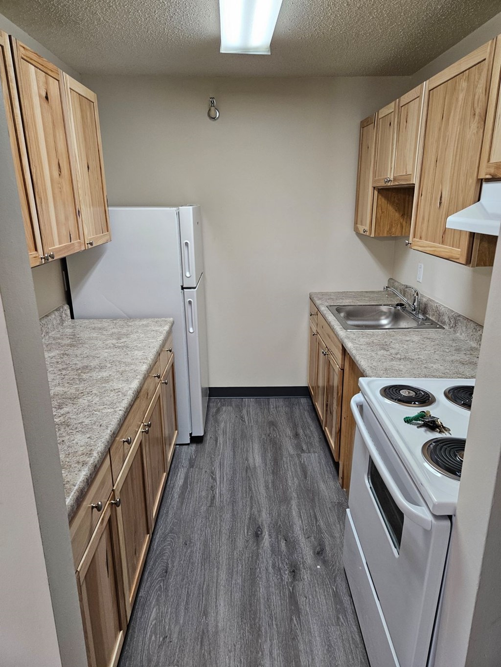 A kitchen with a white stove top oven and a white refrigerator.