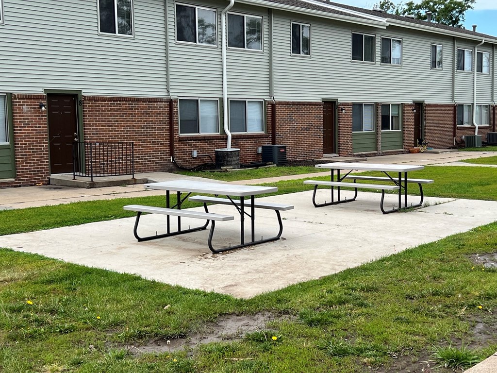 two picnic tables in front of an apartment building