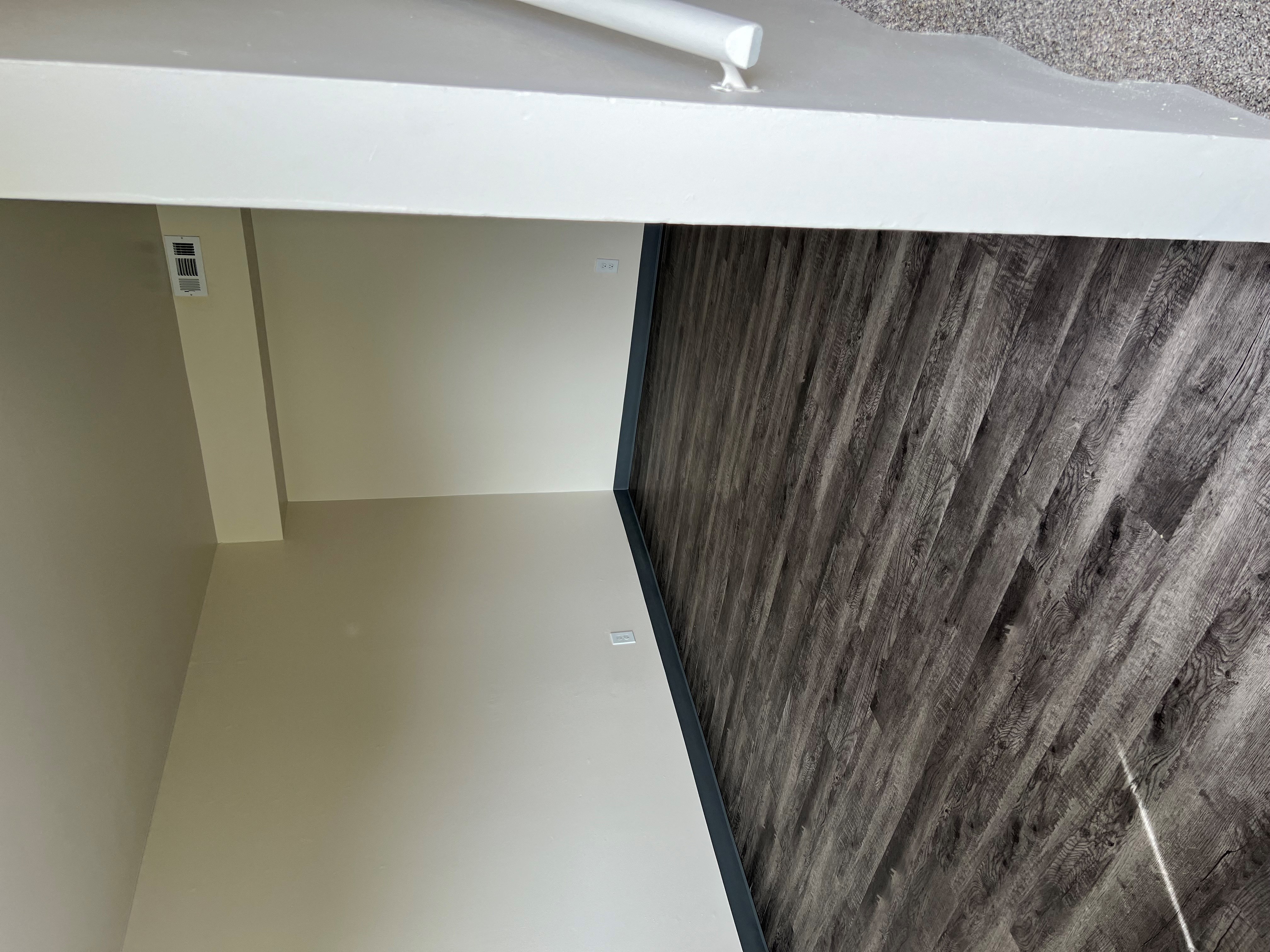 a view of the bottom of a room with a wooden wall and a white counter