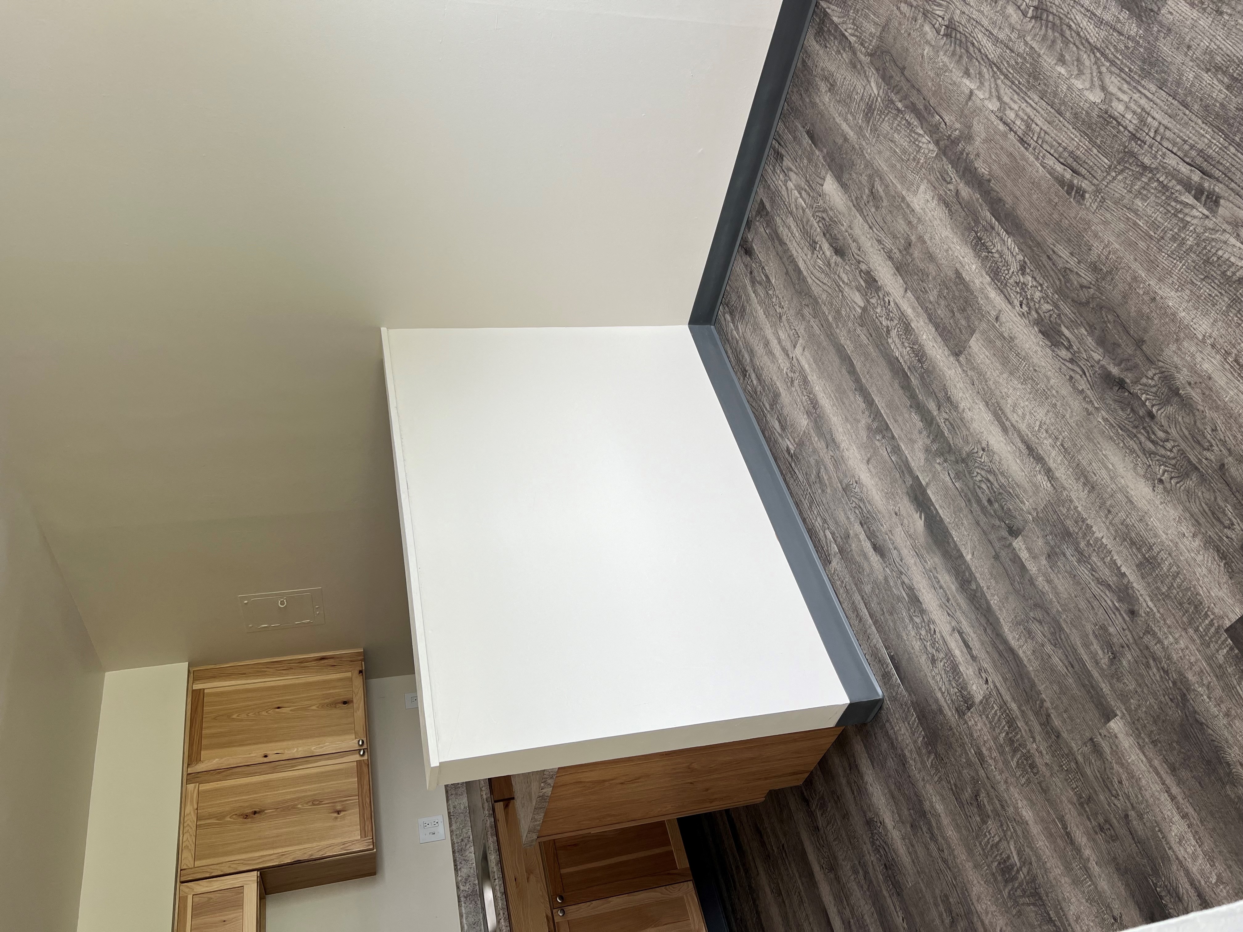 a kitchen with a white counter top and a wooden floor