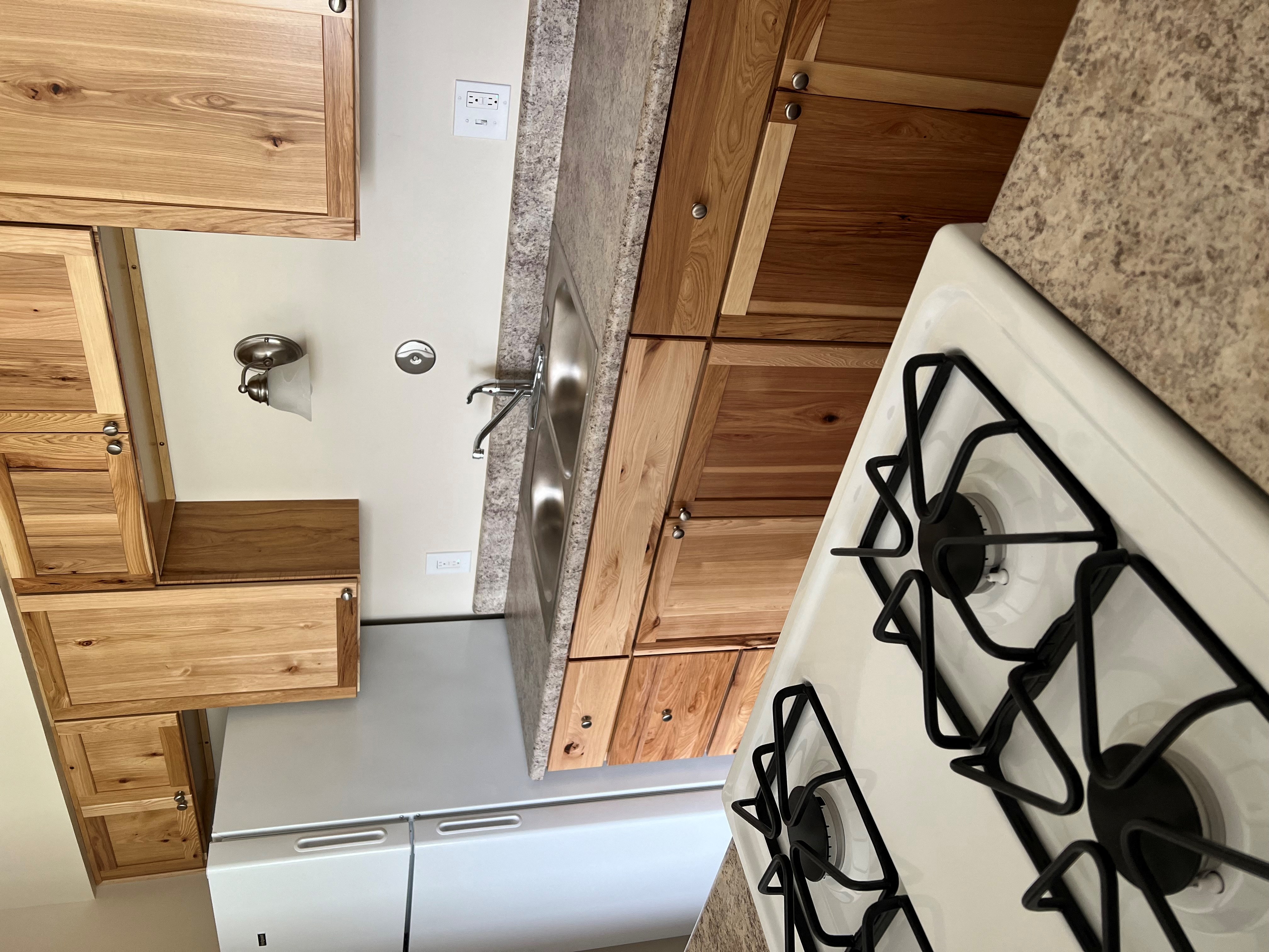 A kitchen with a stove top oven and wooden cabinets.