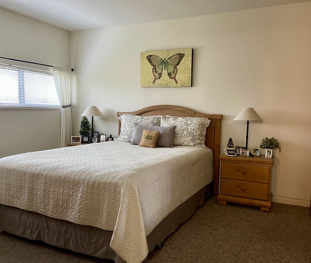A bedroom with a large bed and a butterfly painting on the wall.