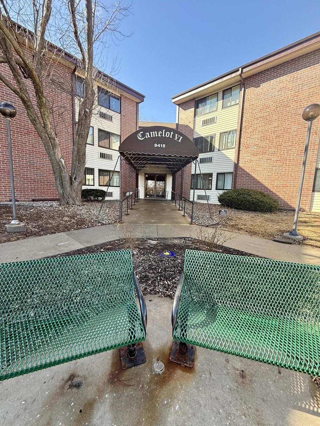 A green mesh fence is in front of a building with a sign that says "Camelot EZ".