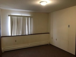 A room with a window covered by vertical blinds.