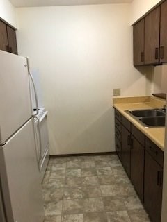 A kitchen with a white refrigerator and brown cabinets.