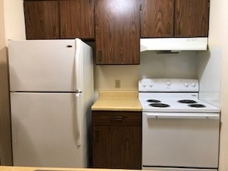 A white refrigerator and stove top oven in a kitchen.