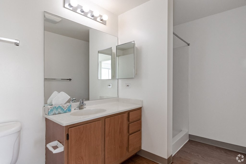 A bathroom with a white sink and brown cabinet.