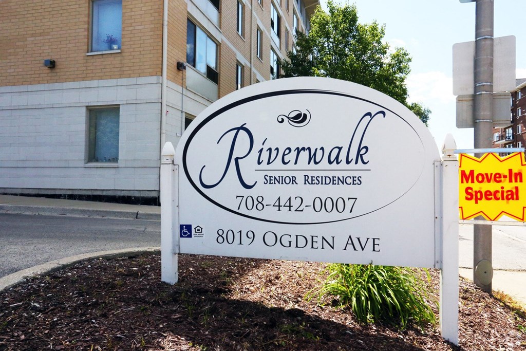 A sign for Riverwalk Senior Residences is displayed in front of a building.