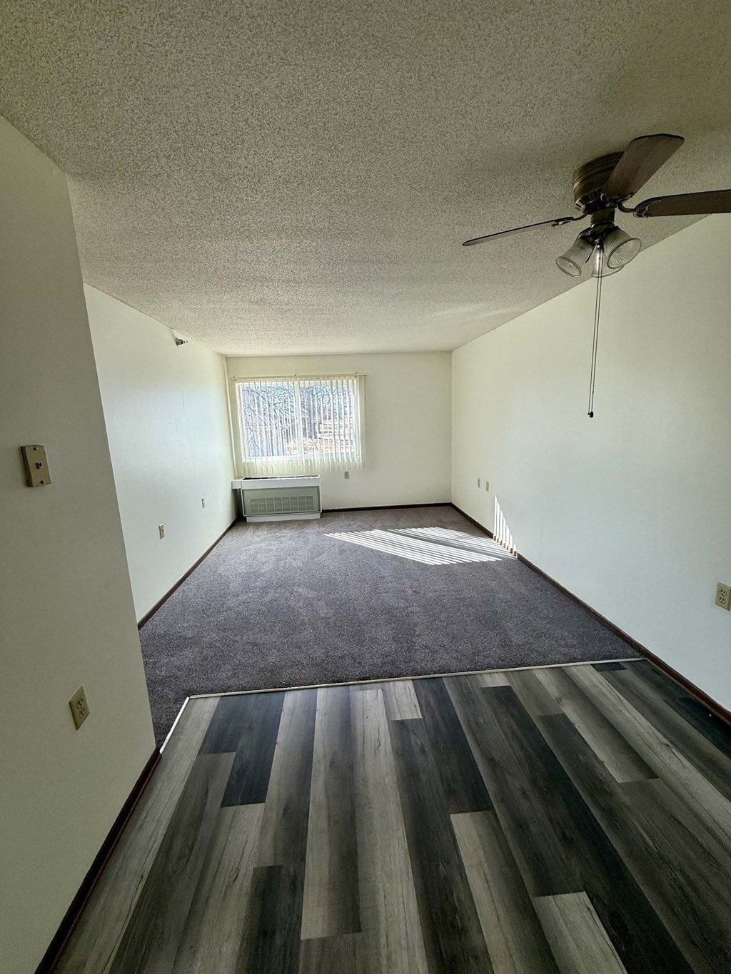 A room with a ceiling fan and a window.