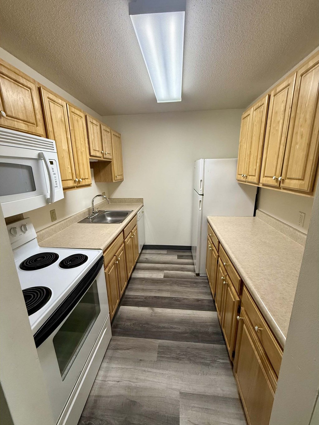 A kitchen with wooden cabinets and a white stove top oven.
