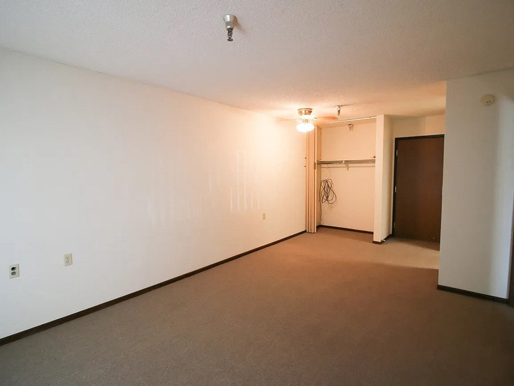 A room with a carpeted floor and a door on the right side.