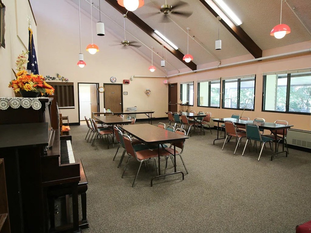 A room with tables and chairs and a piano.