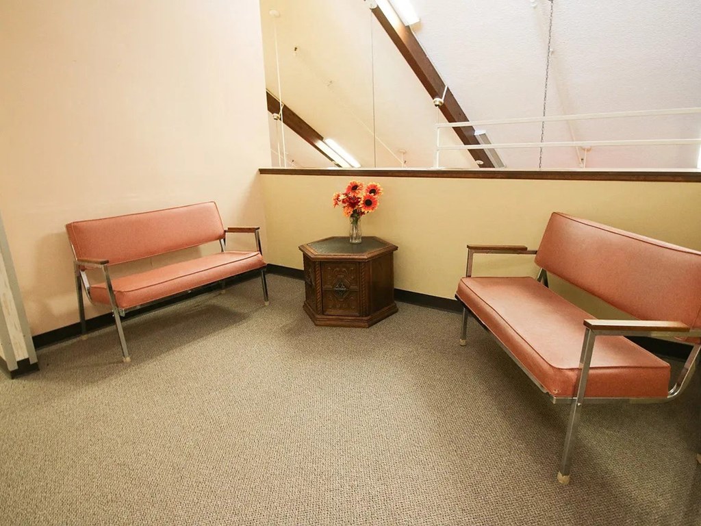 A waiting room with two chairs and a bench.