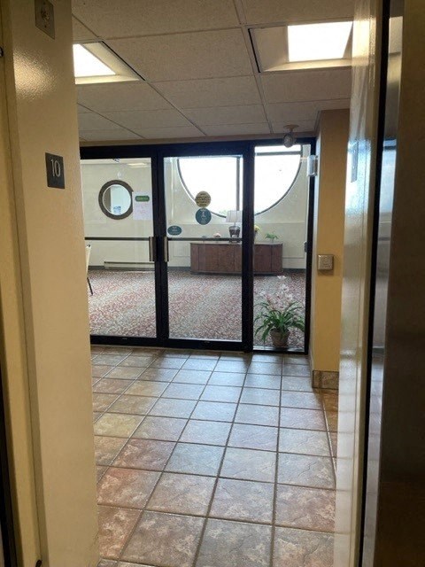 A hallway with a glass door leading to a conference room.