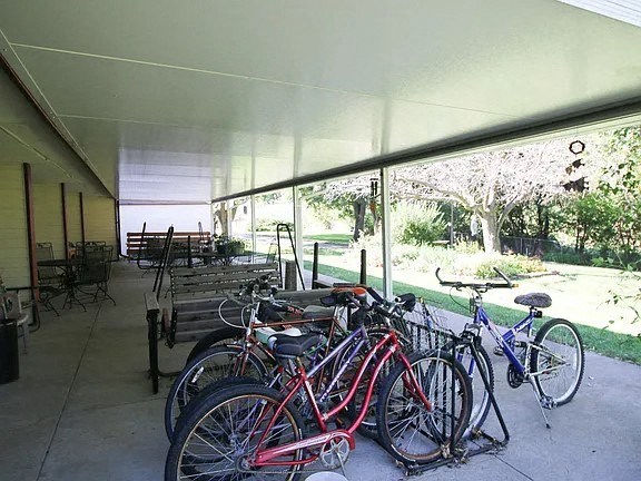 A row of bicycles are parked under a covered walkway.