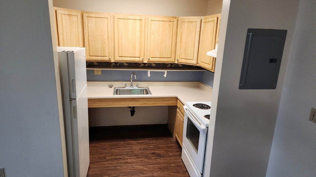 a small kitchen with wood floors and white appliances
