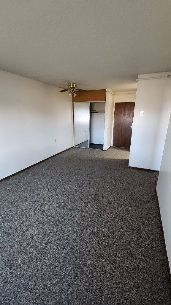 an empty room with a ceiling fan and a door