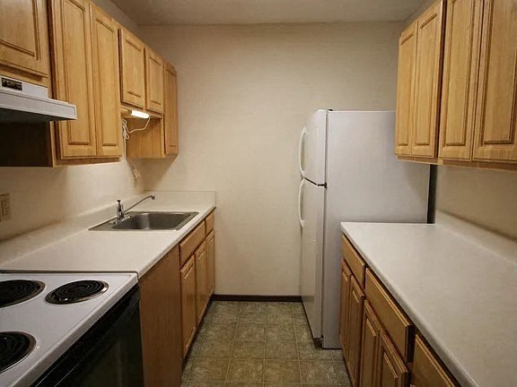 A kitchen with wooden cabinets and a white refrigerator.