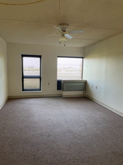 an empty room with a ceiling fan and two windows