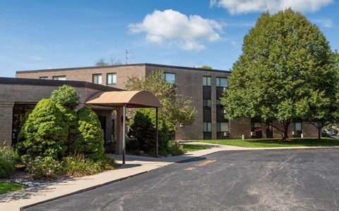 A building with a grey roof and a tree in front of it.