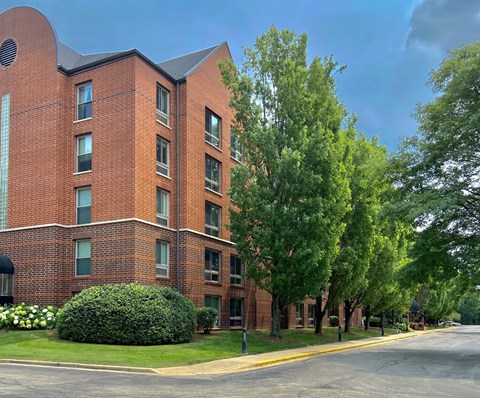 A red brick building with green trees in front.
