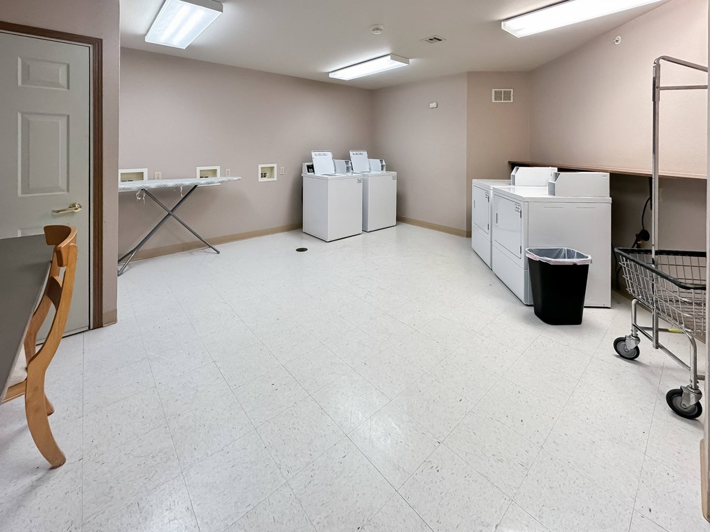a laundry room with washers and dryers in it and a cart in front