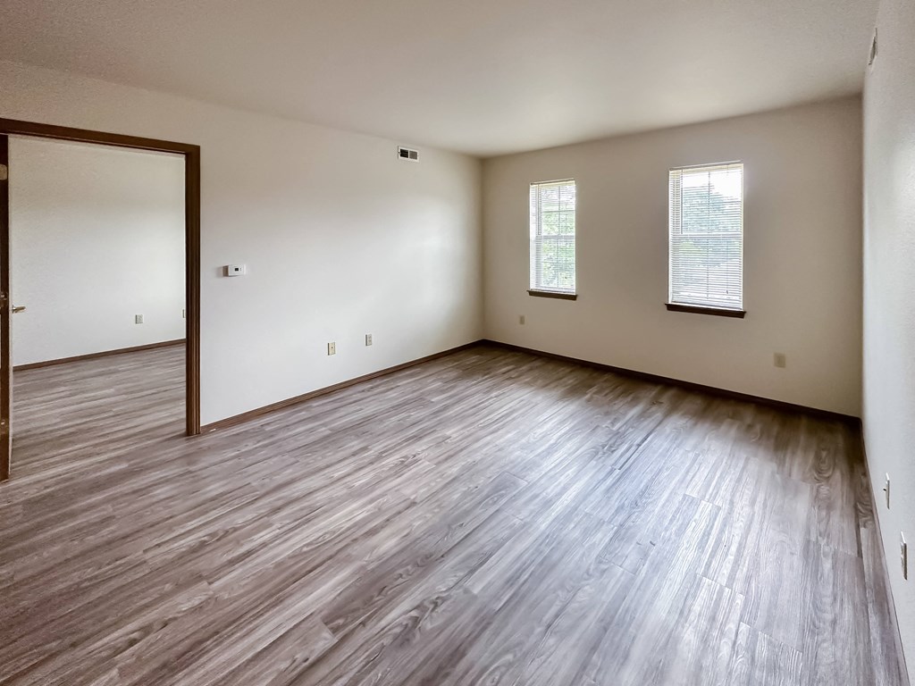 the living room of an empty house with wooden floors and white walls