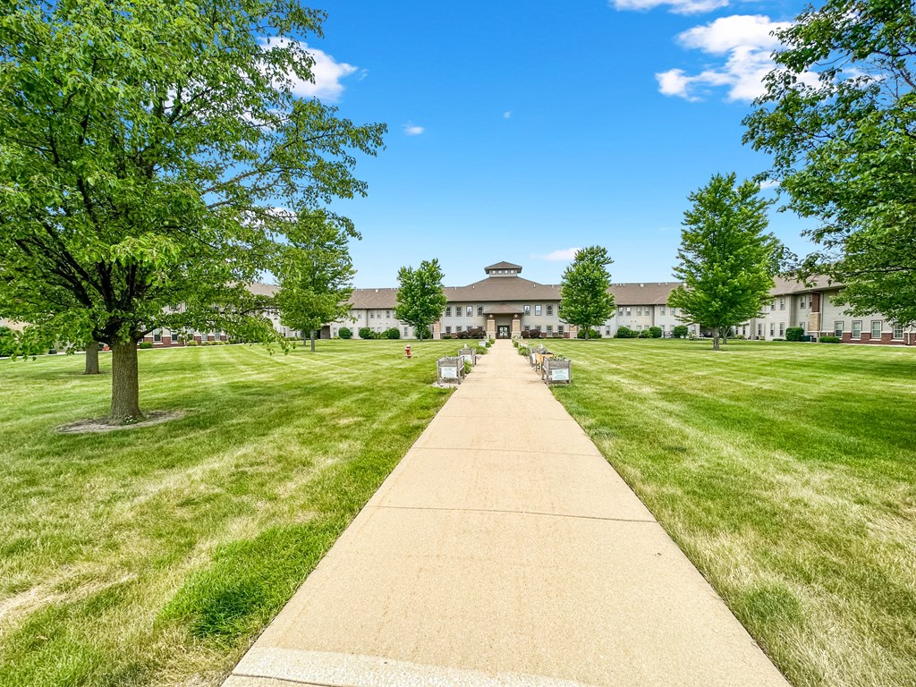 a sidewalk leading to a building with grass and trees