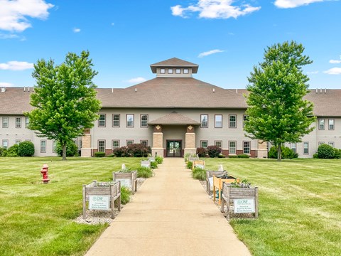 the front of a large building with trees and a sidewalk