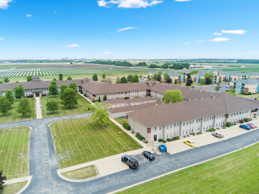an aerial view of a building with a field and cars parked in front of it