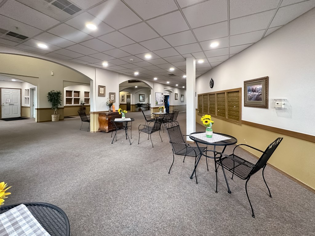 a community room with tables and chairs and a counter with flowers
