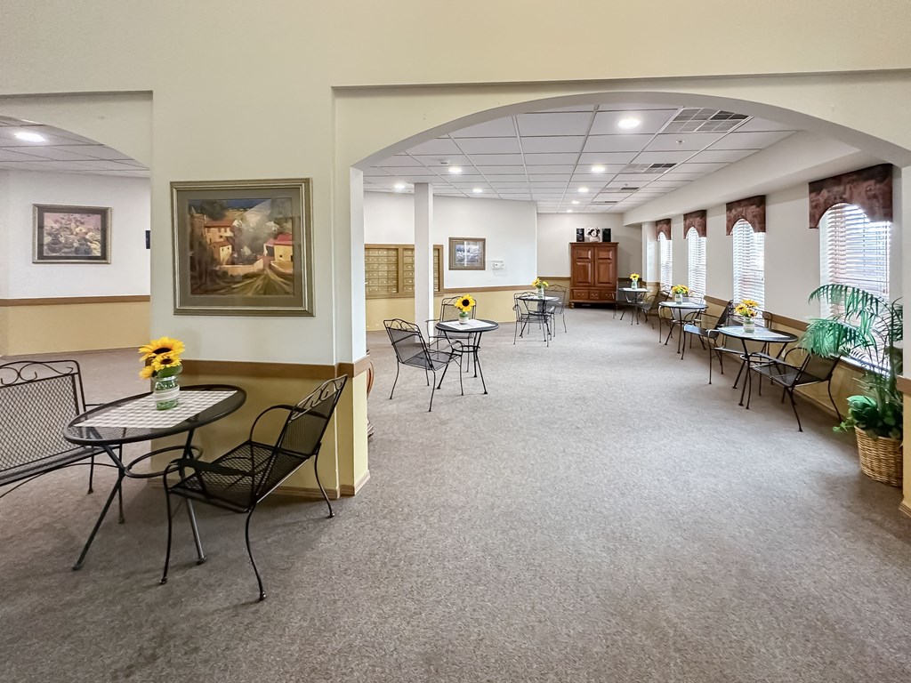 a dining room with tables and chairs and a large room with windows