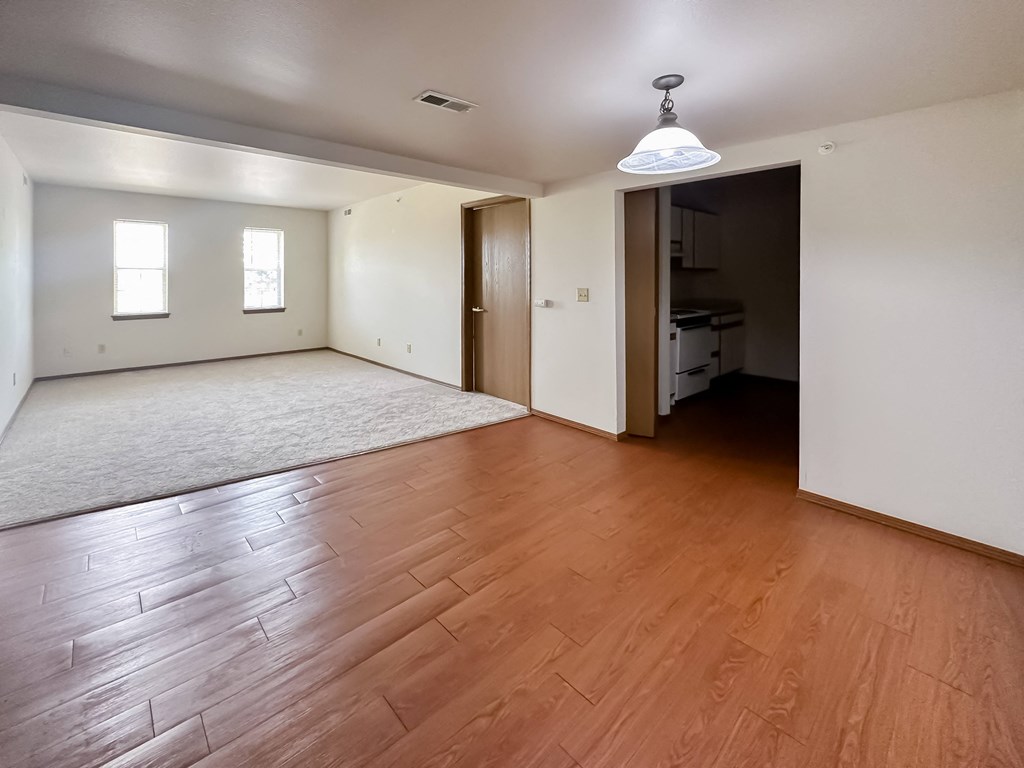 an empty living room with wood flooring and white walls