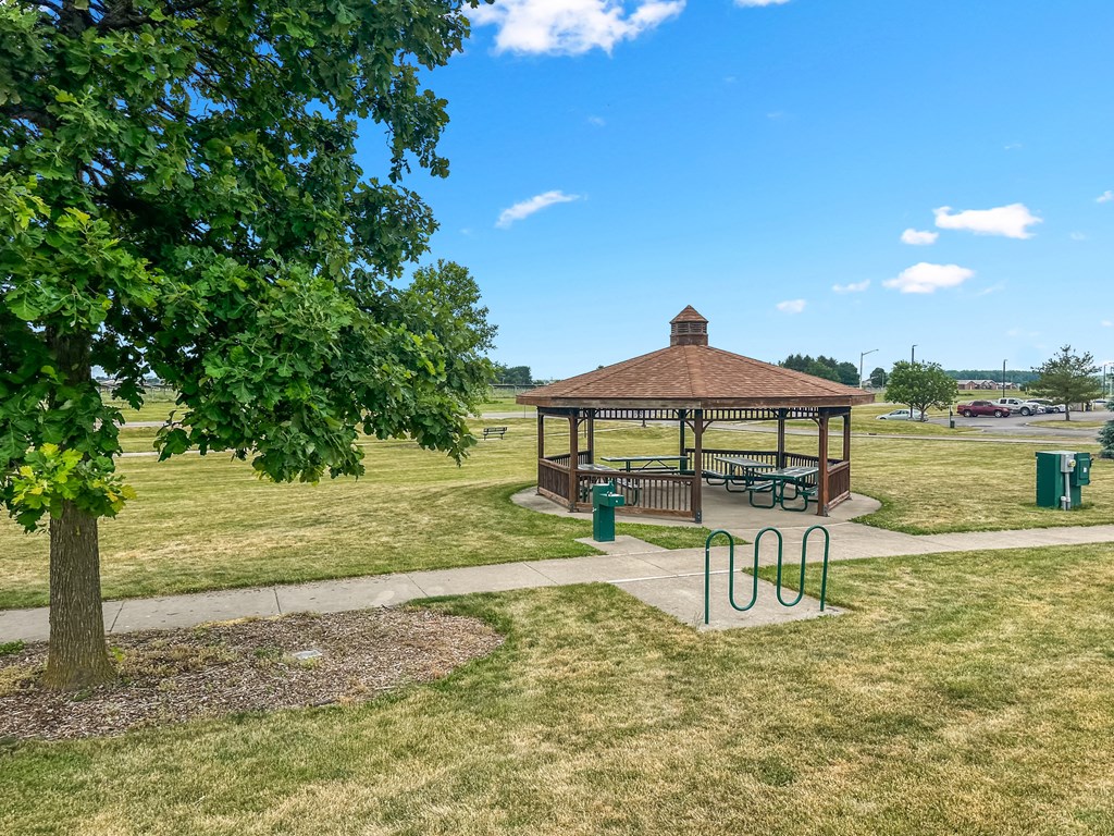a gazebo in a park with a playground and a tree