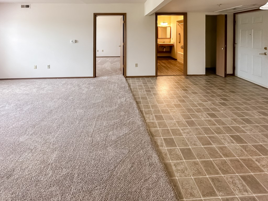 the living room and dining room of a new home with a carpet and tile floor