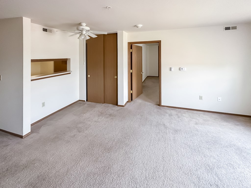 an empty living room with carpet and a ceiling fan