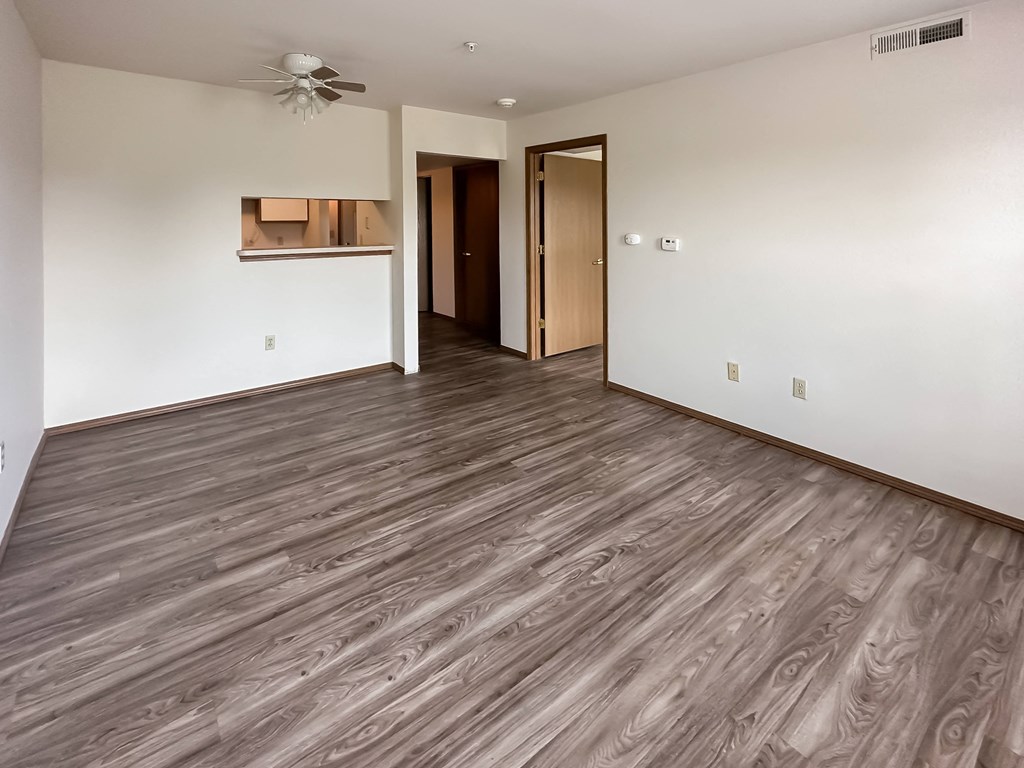 the living room and dining room of an empty house with wood flooring