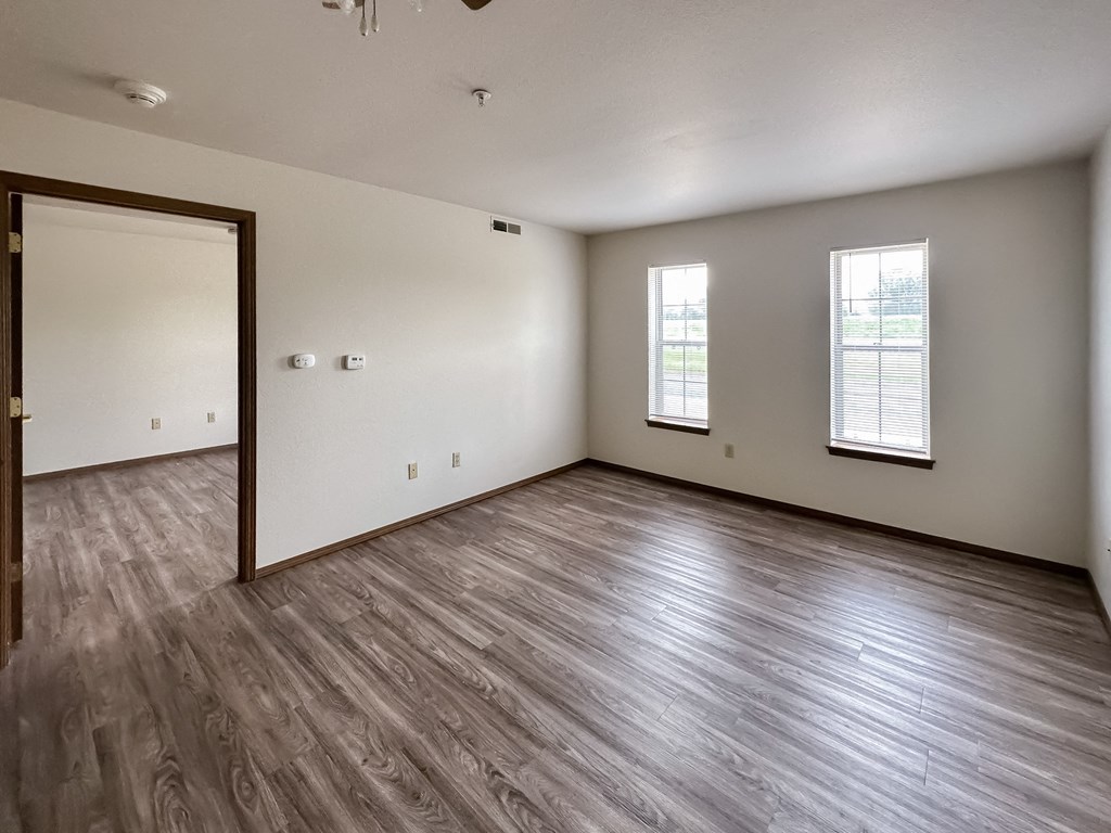 the living room of an empty apartment with wood flooring and a door