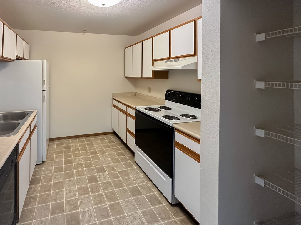 an empty kitchen with white appliances and wood cabinets