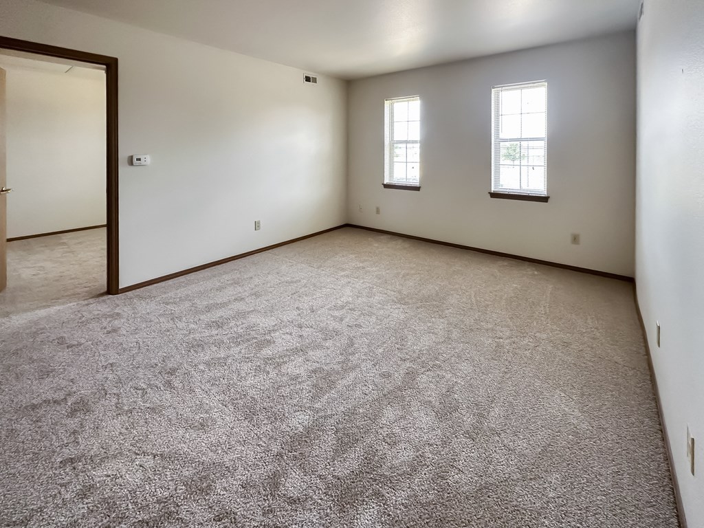 the living room of a home with carpet and a door to a bedroom