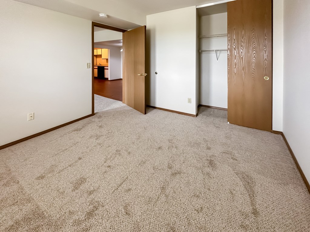 an empty living room with carpet and a door to a bedroom