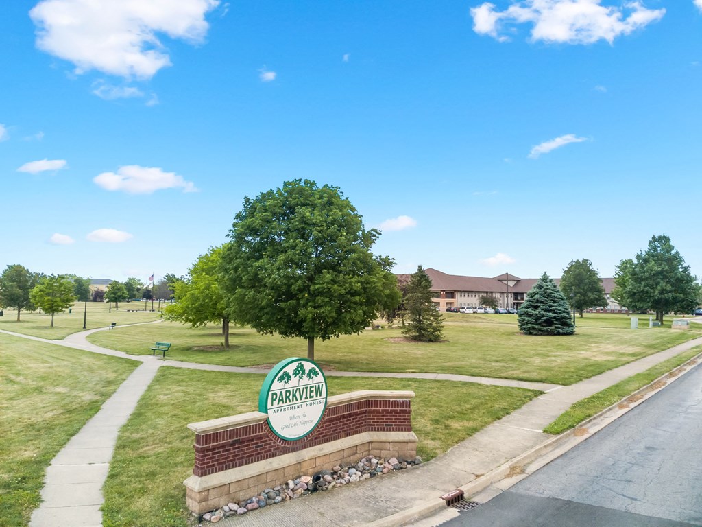 a park with a tree and a sign on the side of a road