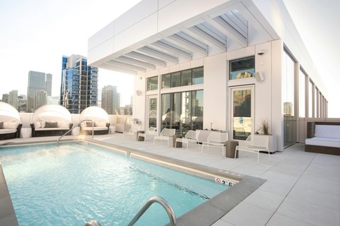 A modern outdoor pool area with a view of the city skyline.