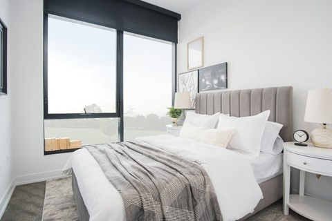 A bedroom with a large bed and a window overlooking a field.