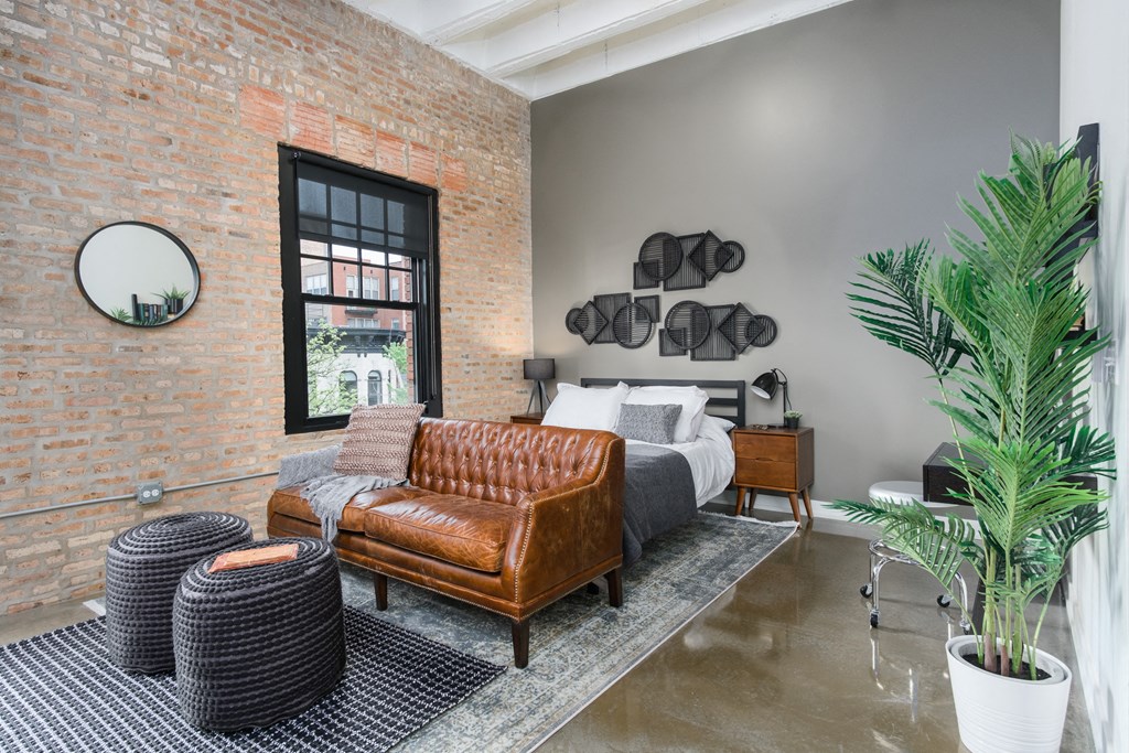 a bedroom with a bed and a couch and a brick wall
