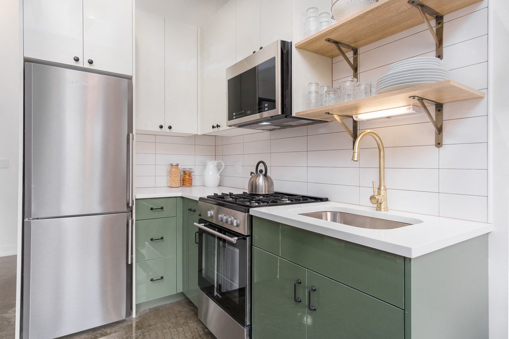 a kitchen with green cabinets and a sink and a refrigerator