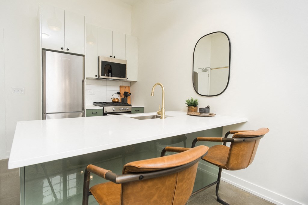 a kitchen with a white counter top and a stainless steel refrigerator