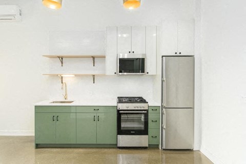a kitchen with green cabinets and a stainless steel refrigerator