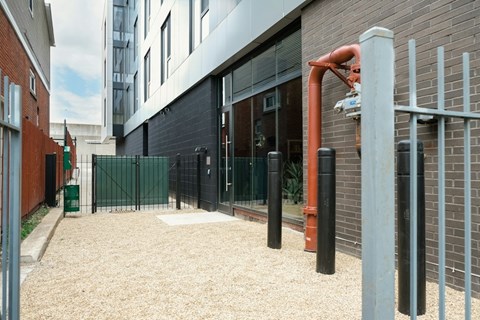 A gravel area in front of a building with a red pipe sticking out of the ground.